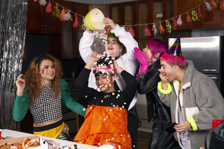A group of friends of varying genders playing with popcorn at a party